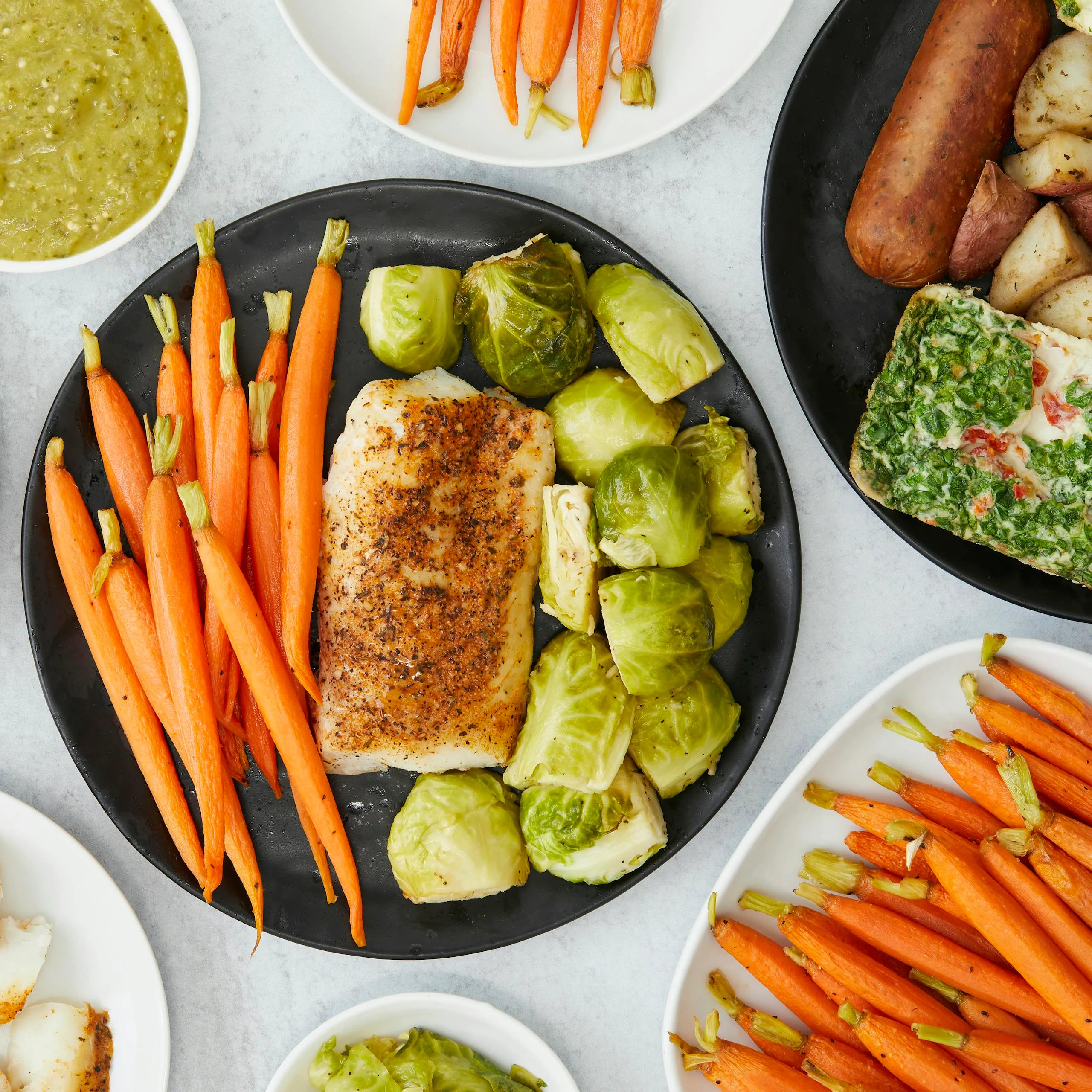 Top view of a healthy meal featuring baked fish, carrots, and Brussels sprouts.