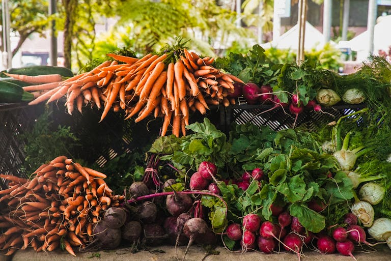 A vibrant display of fresh carrots, radishes, and greens at a local outdoor market.
