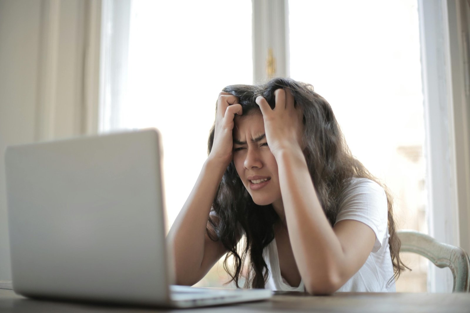 woman holding her head in frustration representing chronic stress and poor recovery
