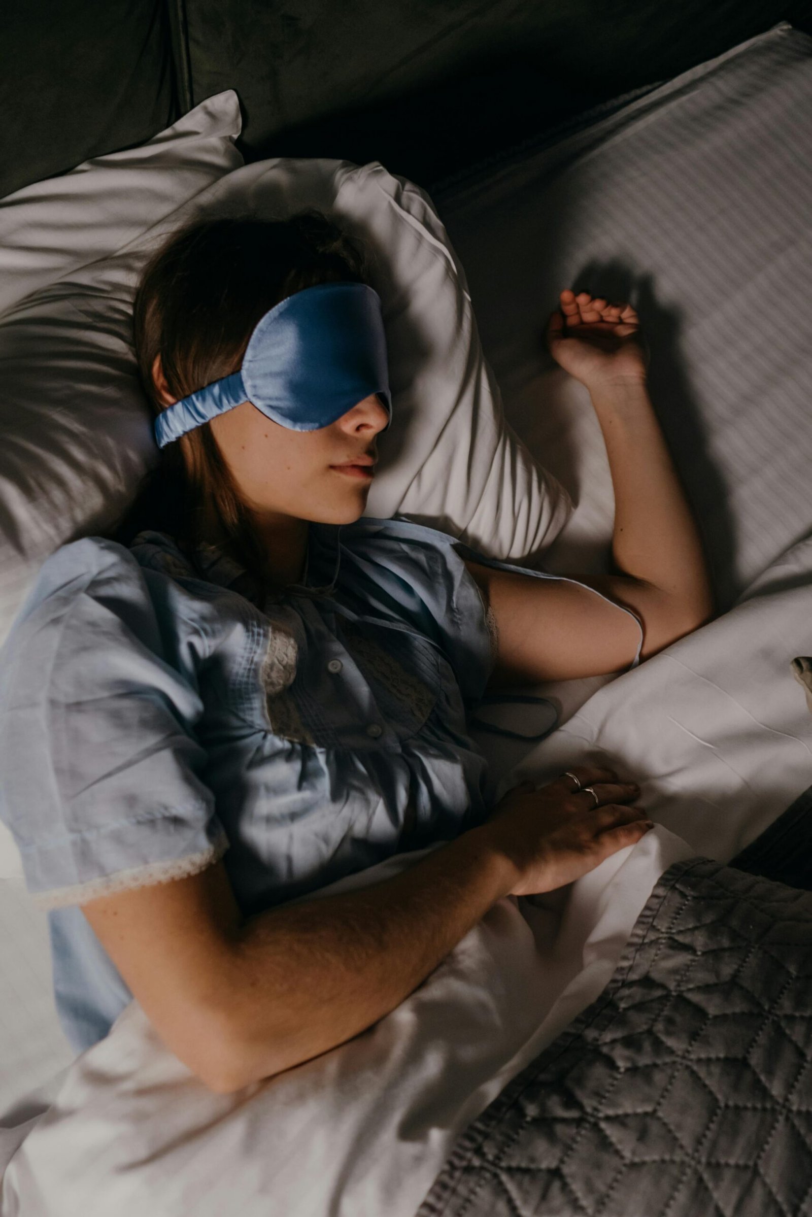 woman sleeping with eye mask in dark bedroom supporting deeper sleep and recovery